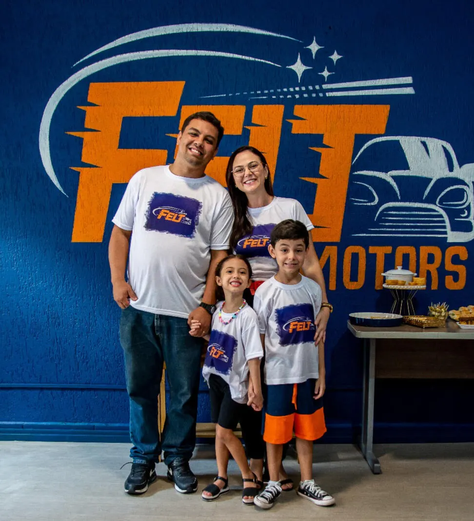 Erick, Fabiane, Laís e Theo com a camiseta da Felt Motors, em frente ao logo pintado na parede da loja